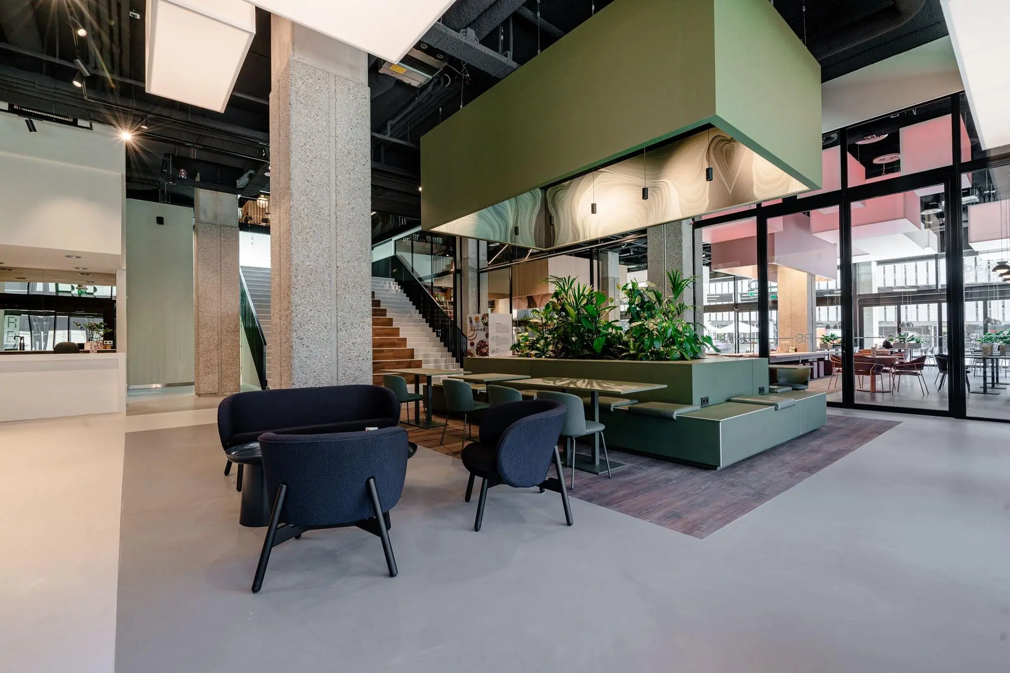 Moderne en open ingerichte lobby aan de Aert van Nesstraat met zitjes, planten en een trap naar de bovenverdieping.